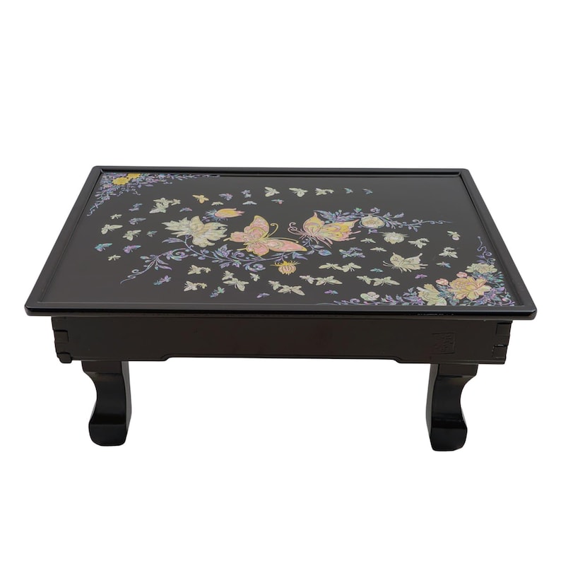 Black rectangular tray with colorful floral and butterfly design, placed on four short legs.