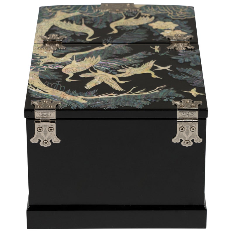 A jewelry box with a black lacquer finish and mother-of-pearl inlay, featuring cranes and pine trees, with silver-colored metal clasps and hardware.