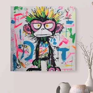 May include: A vibrant pop art canvas featuring a monkey with a mohawk and pink spectacles. The monkey is depicted in black with green and pink details. The background is white, adorned with colourful graffiti-style splatters.