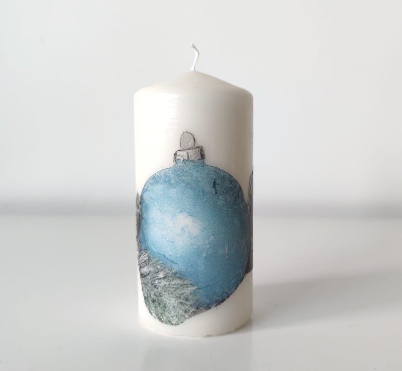May include: White candle with a blue and gray Christmas ornament design.