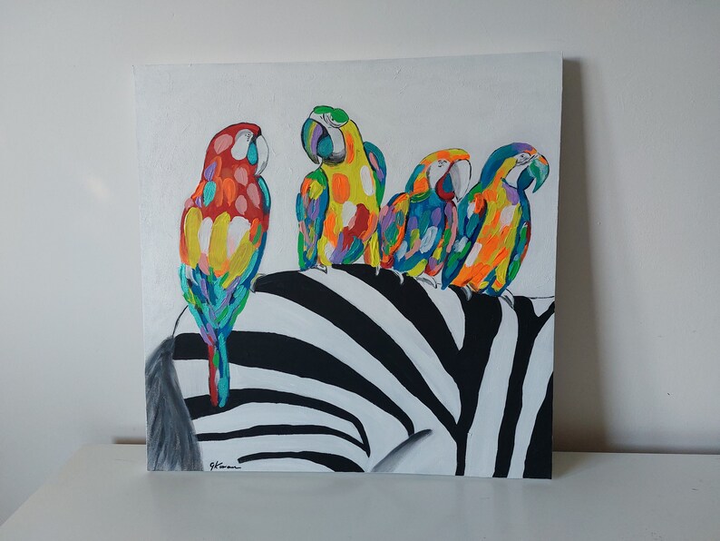 May include: A painting of four colorful parrots perched on a black and white zebra. The parrots are painted in shades of red, yellow, blue, and green.