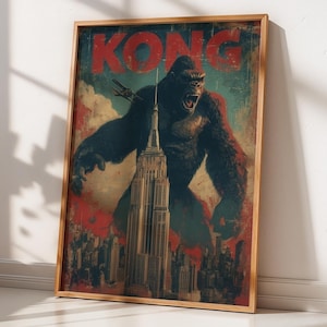 May include: A framed vintage-style poster featuring King Kong atop the Empire State Building. The word "KONG" is in large red letters at the top. The artwork has a distressed look with a color palette of red, blue, and brown.