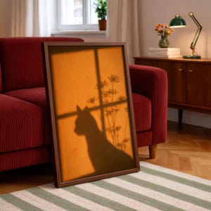 Cat shadow poster featuring a minimalist orange silhouette of a cat sitting by a sunlit window, with soft plant shadows on a textured amber wall. Moody aesthetic wall art perfect for bedrooms, reading nooks, or hallways. Warm sunset-toned cat silhouette print, a unique gift for cat lovers who enjoy dreamy, atmospheric wall decor rather than literal pet portraits.
