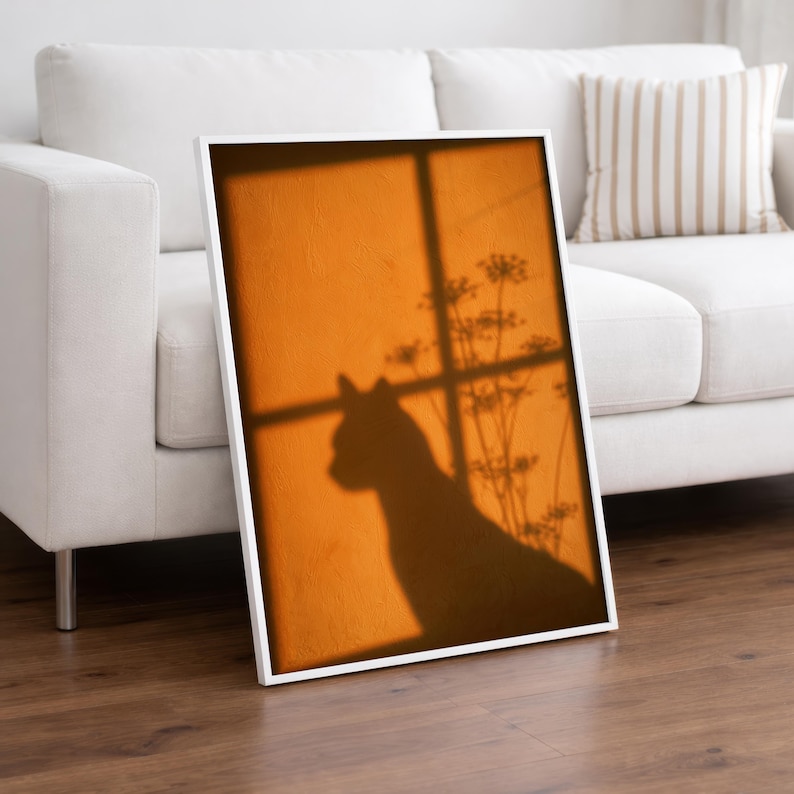 Cat shadow poster featuring a minimalist orange silhouette of a cat sitting by a sunlit window, with soft plant shadows on a textured amber wall. Moody aesthetic wall art perfect for bedrooms, reading nooks, or hallways. Warm sunset-toned cat silhouette print, a unique gift for cat lovers who enjoy dreamy, atmospheric wall decor rather than literal pet portraits.