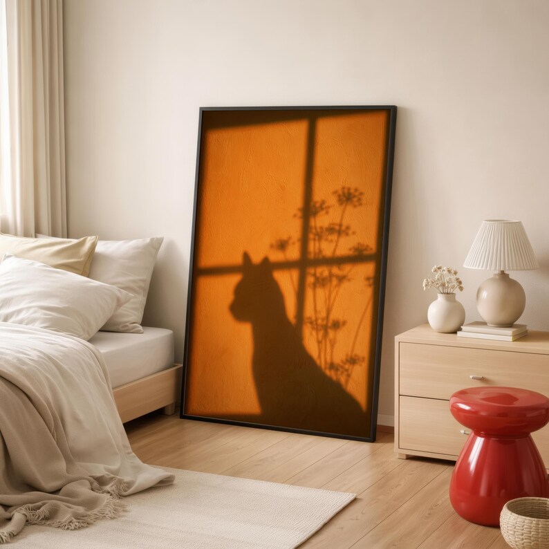 Cat shadow poster featuring a minimalist orange silhouette of a cat sitting by a sunlit window, with soft plant shadows on a textured amber wall. Moody aesthetic wall art perfect for bedrooms, reading nooks, or hallways. Warm sunset-toned cat silhouette print, a unique gift for cat lovers who enjoy dreamy, atmospheric wall decor rather than literal pet portraits.