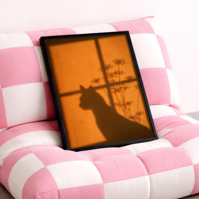 Cat shadow poster featuring a minimalist orange silhouette of a cat sitting by a sunlit window, with soft plant shadows on a textured amber wall. Moody aesthetic wall art perfect for bedrooms, reading nooks, or hallways. Warm sunset-toned cat silhouette print, a unique gift for cat lovers who enjoy dreamy, atmospheric wall decor rather than literal pet portraits.