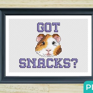 May include: Cross stitch pattern featuring a guinea pig with the text "GOT SNACKS?" in purple lettering.