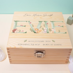May include: A wooden keepsake box with a personalised inscription for a baby named Evie. The box is decorated with a leafy design and woodland animal illustrations. The inscription reads "Evie Marie Smith, 14th January 2024, Weighing 7lb 4oz, Born at 12:14PM".
