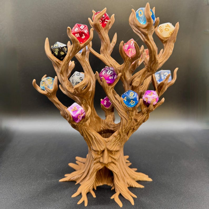 Peut inclure: Un pr&eacute;sentoir &agrave; d&eacute;s en forme d'arbre brun, avec de multiples branches tenant chacune un d&eacute; &agrave; plusieurs faces. Les d&eacute;s sont de couleurs vari&eacute;es, notamment rouge, bleu et violet. L'arbre a un visage sculpt&eacute; dans le tronc.