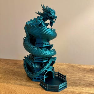 May include: A teal blue 3D printed dragon wrapped around a pagoda-style tower with a hexagonal base. The dragon's head is at the top of the tower, and the tail wraps around the bottom.