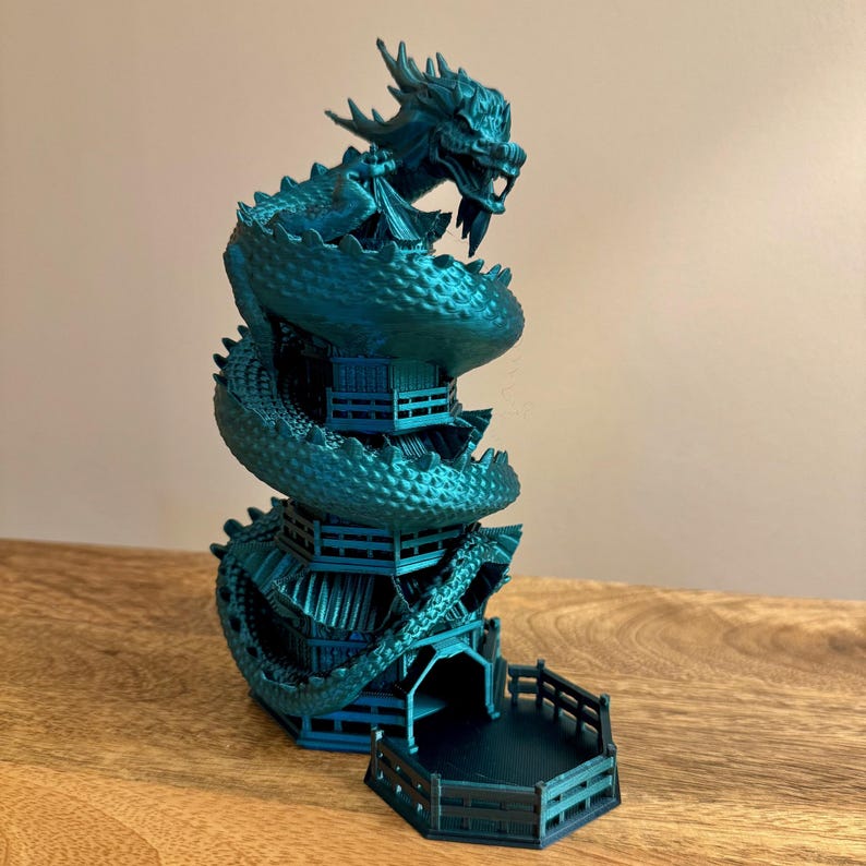 May include: A teal blue 3D printed dragon wrapped around a pagoda-style tower with a hexagonal base. The dragon's head is at the top of the tower, and the tail wraps around the bottom.