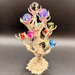 May include: A beige, skeletal tree-shaped dice holder with multiple branches, each holding a colourful, multi-sided die. The dice are various colours, including blue, pink, and yellow. The base of the tree features several small skulls.