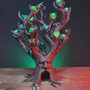 Peut inclure: Un support &agrave; d&eacute;s en forme d'arbre peint &agrave; la main. Le support est principalement marron avec des accents rouges, avec un visage sculpt&eacute; dans le tronc et des branches contenant divers d&eacute;s verts et bleus. Le support &agrave; d&eacute;s est pos&eacute; sur une surface en bois.
