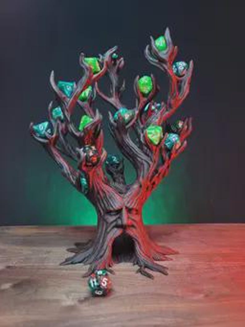 Peut inclure: Un support &agrave; d&eacute;s en forme d'arbre peint &agrave; la main. Le support est principalement marron avec des accents rouges, avec un visage sculpt&eacute; dans le tronc et des branches contenant divers d&eacute;s verts et bleus. Le support &agrave; d&eacute;s est pos&eacute; sur une surface en bois.