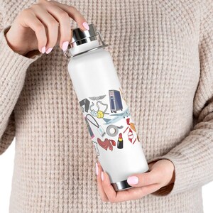 May include: White stainless steel water bottle with a colorful design featuring airplane, luggage, and other travel-related icons.