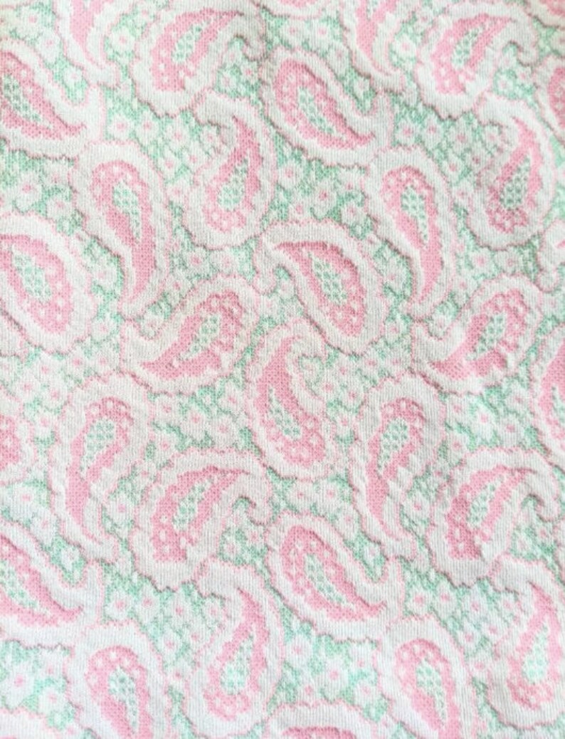 May include: White fabric with a pink and green paisley pattern.