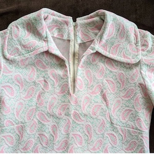 May include: A pink and green paisley patterned dress with a long zipper down the front.