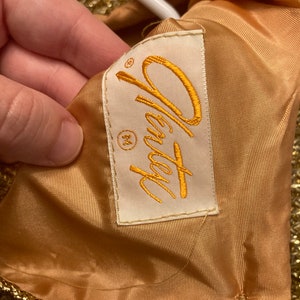 May include: A gold sequined dress with a white label that says "Oleg Cassini" and a size "M" tag.