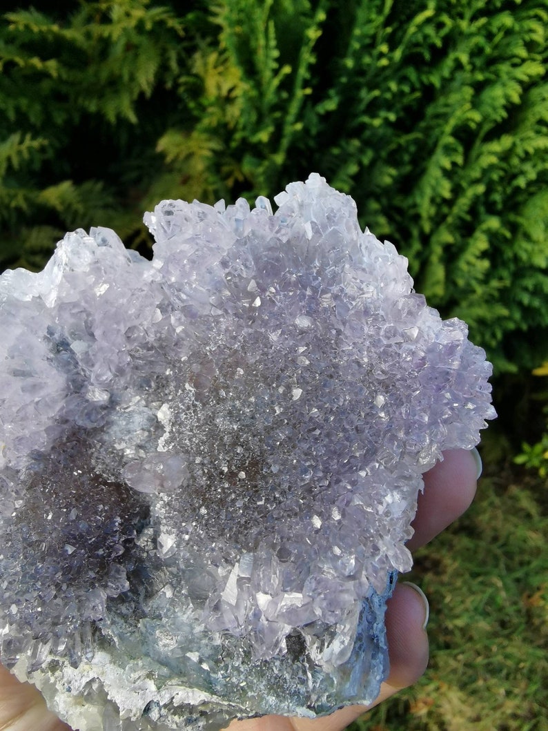 May include: A cluster of amethyst crystals with a purple and white color. The crystals are arranged in a cluster and have a rough, natural texture.
