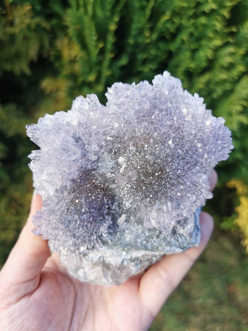 May include: A cluster of amethyst crystals with a purple and white color. The crystals are arranged in a flower-like shape and have a rough, natural texture.