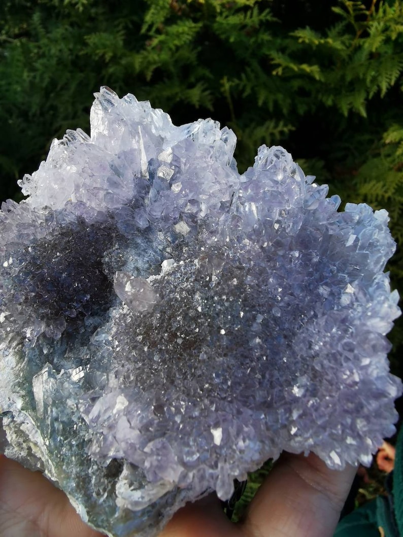 May include: A large amethyst crystal cluster with a purple and white color. The crystal has a rough, natural texture and is surrounded by smaller crystals.