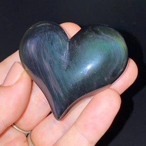 Puede incluir: Un cristal de obsidiana en forma de coraz&oacute;n con colores arco&iacute;ris iridiscentes. El cristal est&aacute; pulido y liso.