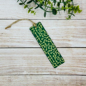 Pode incluir: Marca-páginas verde com um design de placa de circuito amarelo.