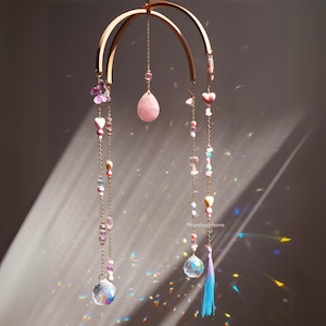 Könnte beinhalten: Ein rosa-goldenes Kristall-Mobile mit einem Holzring, rosa Herzperlen und Kristalltropfen. Das Mobile hängt von der Decke und wirft Regenbögen an die Wand.