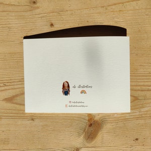 May include: A blank white card with a small illustration of a person with red hair and a rainbow. The text "els illustrations" is written below the illustration.
