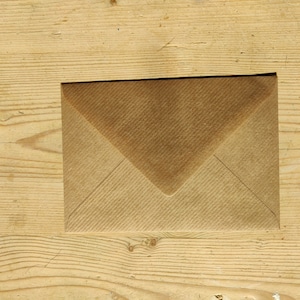 May include: A brown paper envelope on a wooden surface.