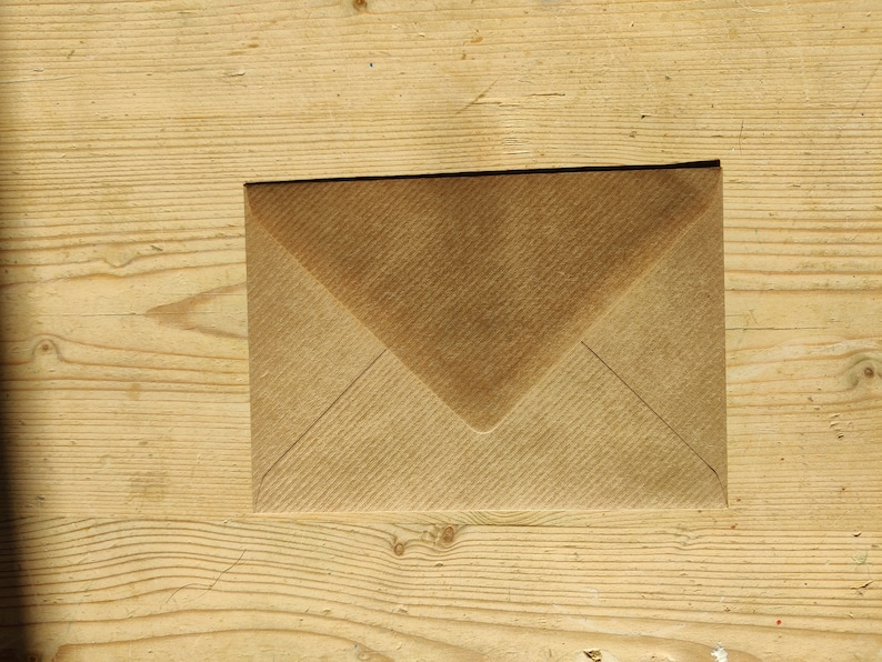 May include: A brown paper envelope on a wooden surface.