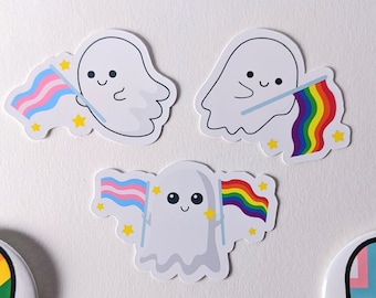 May include: Three ghost stickers with rainbow and transgender pride flags. Each ghost is holding a flag and has a cute, smiling face.