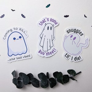 May include: Three ghost-themed stickers with different sayings. The first sticker says "Coming to KILL... your bad vibes!" The second sticker says "That's some BOO'S sheet!" The third sticker says "Snuggles til' I die!"
