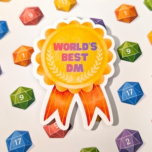 May include: A sticker with the text "WORLD'S BEST DM" in purple and orange, surrounded by a gold laurel wreath and orange ribbons. Scattered around are colorful, multi-sided dice with numbers.