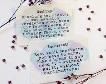 May include: Two watercolor cards with inspirational quotes about taking breaks. The top card is in German and says "Wichtig: Erholung ist nichts, was man sich verdienen muss. Nimm dir Pausen, wenn du sie brauchst - ohne Schuldgefühle, ohne Rechtfertigung." The bottom card is in English and says "Important: Rest isn't something you have to earn. Take a break if you need it - without guilt, without explanations."