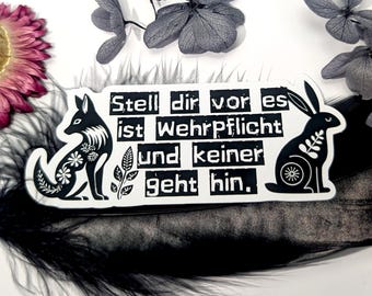 May include: A black and white sticker featuring a fox and a rabbit with floral and skeletal designs. The sticker has the German text "Stell dir vor es ist Wehrpflicht und keiner geht hin." Decorative elements include dried flowers and a black feather.
