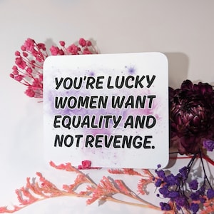 Peut inclure: Un autocollant blanc avec un fond aquarelle violet et rose. Le texte sur l'autocollant est "You're lucky women want equality and not revenge."