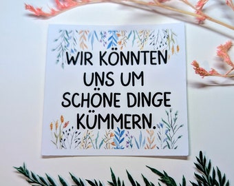 May include: White card with a floral border and the text "Wir konnten uns um schöne Dinge kümmern." in black lettering.