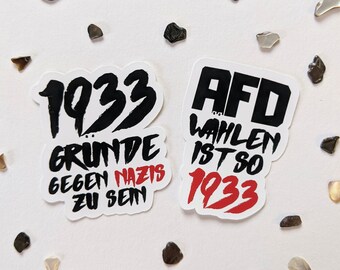 May include: Two black and white stickers with red text. The first sticker says "1933 Gründe gegen Nazis zu sein". The second sticker says "AfD Wahlen ist so 1933".