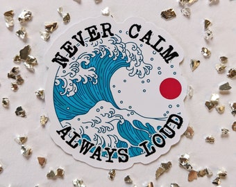 May include: A white sticker with a blue and white wave design and a red circle. The text "Never Calm Always Loud" is written around the wave.
