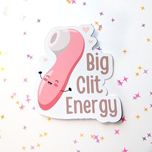 May include: Pink sticker with a cartoon illustration of a pink toy with a smiling face and the text "Big Clit Energy".