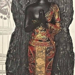 May include: Black Buddha statue with gold accents, sitting in a black rock formation. The statue is wearing a red and gold robe with intricate patterns.