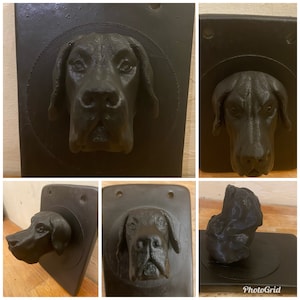 Puede incluir: Un conjunto de cuatro placas de pared negras con cabezas de perro impresas en 3D. Cada placa tiene un recorte circular alrededor de la cabeza del perro.