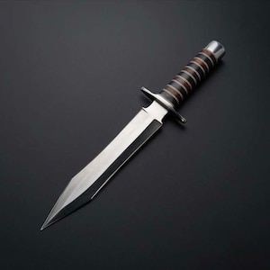 May include: A silver knife with a black and brown handle. The blade is long and sharp, and the handle is wrapped in leather.