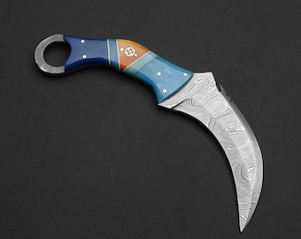Può includere: Un coltello curvo argentato con un manico blu, arancione e bianco. Il manico ha un anello nella parte superiore per una presa facile.