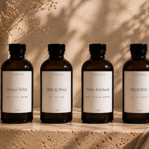May include: Four amber glass bottles with black caps and white labels, each labelled SCENTRO. The labels read Rouge Eclat, Milk & Petal, White Patchouli, and IMAGINE. Each bottle has a 200ml capacity printed at the bottom of the white label.