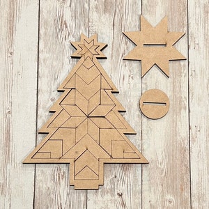 May include: A wooden Christmas tree ornament with a geometric design. The ornament is made of multiple pieces that fit together to create a 3D effect. The ornament also includes a separate star and a round base.