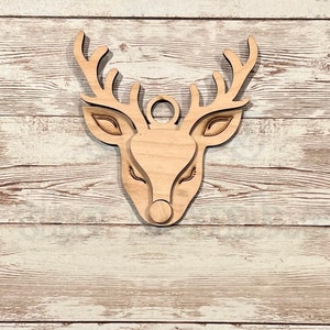 May include: Wooden reindeer head ornament with a brown stain. The reindeer has large antlers and a red nose.