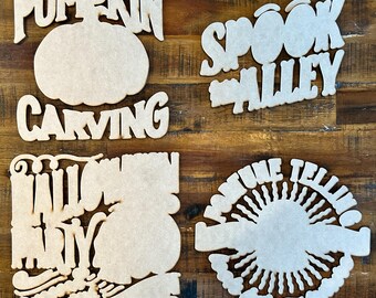 May include: Four unfinished wooden signs with Halloween themes. The signs read "Pumpkin Carving", "Spook Alley", "Halloween Party", and "Fortune Telling".