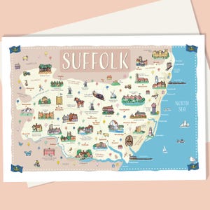 Peut inclure: Une carte illustrée de Suffolk, en Angleterre, représentant les villes, les monuments et la mer du Nord. La carte est ornée de drapeaux et de petites illustrations, avec le mot "Suffolk" en évidence.